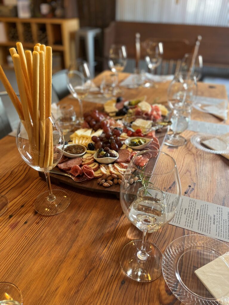 Charcuterie board with meats, cheeses, grapes, and wine glasses set for an elevated tasting at Adam Puchta Winery