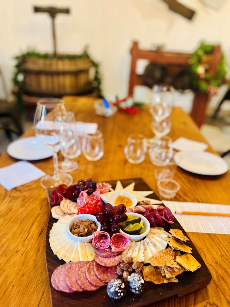 Charcuterie board with meats, cheeses, fruit, and wine glasses in the tasting room at Adam Puchta Winery