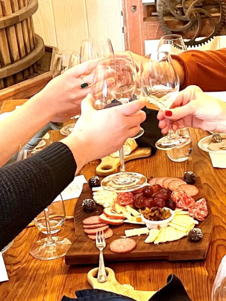 Guests toasting wine glasses over a charcuterie board during an elevated tasting at Adam Puchta Winery